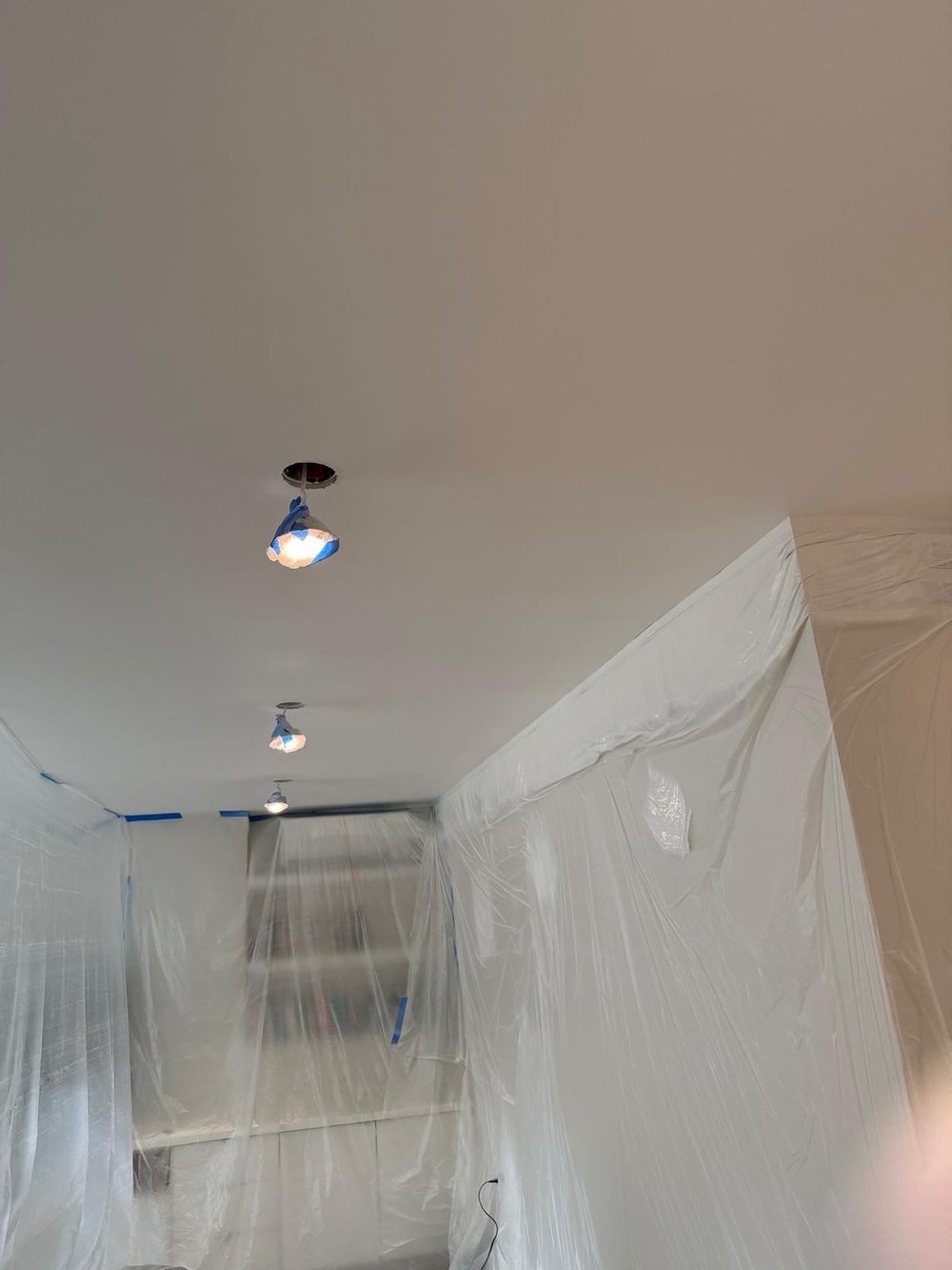 Room masked in plastic with the repaired ceiling painted to match the rest